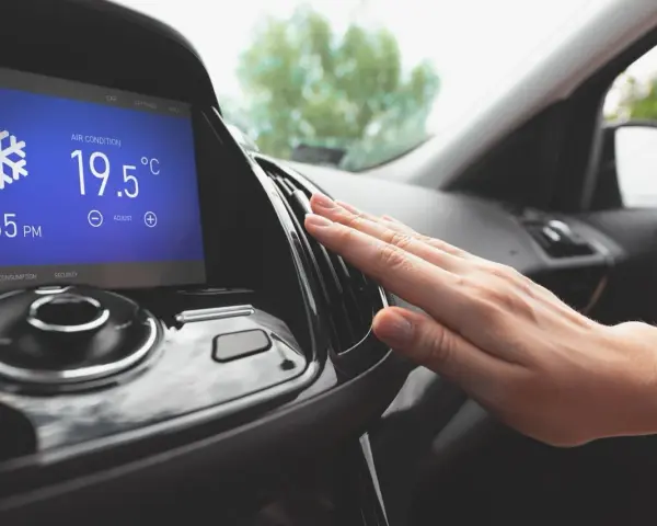Main d'une personne vérifiant la sortie d'air climatisé dans une voiture, affichant 19.5°C. Parfait pour le clim air chaud.