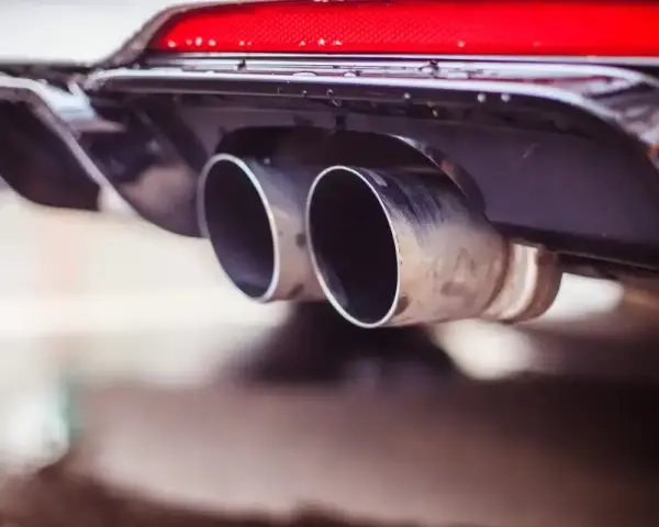 Double sortie d'échappement d'une voiture. La question "peut-on rouler avec un catalyseur défectueux" se pose face à ces gaz d'échappement.