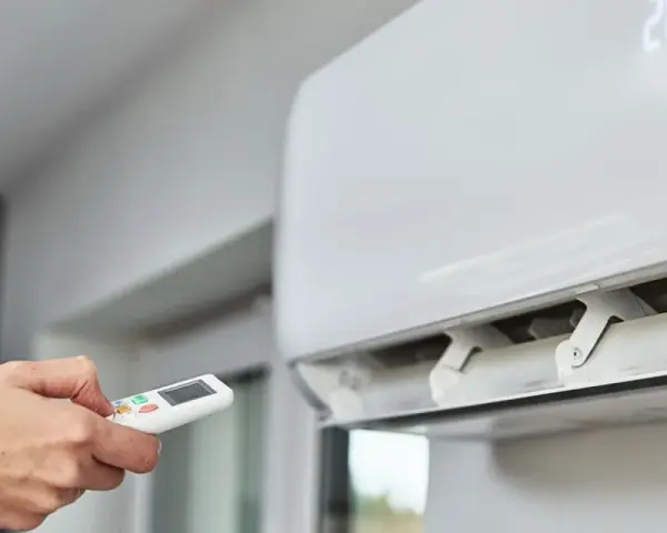Main tenant utilise la télécommande pour régler la climatisation. Un problème climatisation voiture ? Ici, c'est pour une maison.