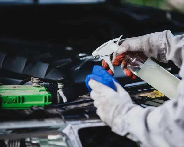 Gants et chiffon bleu pour comment nettoyer un moteur de voiture plein d'huile. Vaporisation d'un produit sur le moteur.