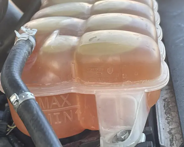 Le réservoir de liquide de refroidissement est plein, indiquant trop de liquide de refroidissement. Les marques MAX et MIN sont visibles.