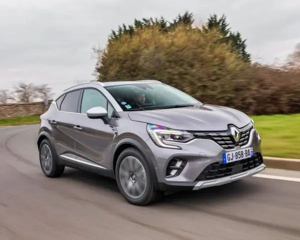 Une Renault Captur 2 grise roule sur une route sinueuse, prête pour son programme d'entretien.