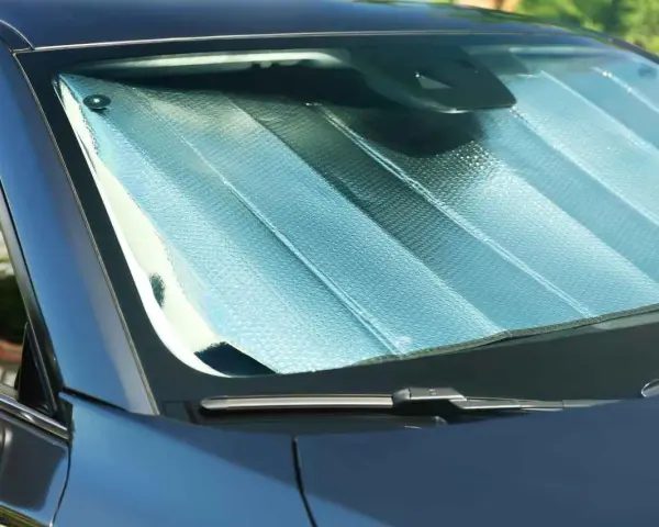 Pare-soleil argenté installé sur un pare-brise de voiture. Facile à mettre, il protège de la chaleur.