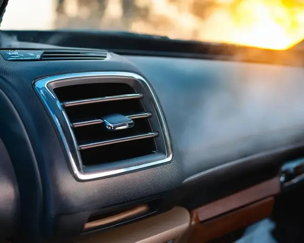 Le tableau de bord d'une voiture moderne, avec une grille de ventilation chromée. L'AC, ou climatisation, permet de réguler la température intérieure.