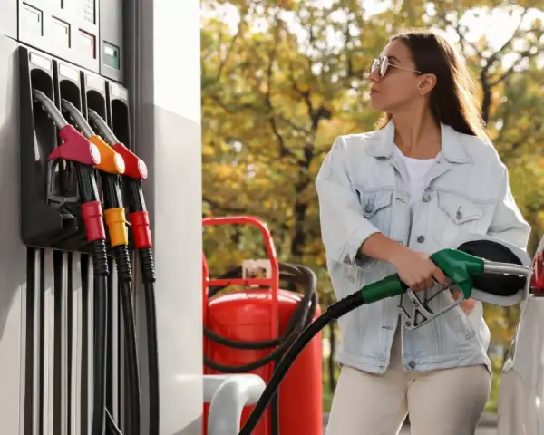 Femme faisant le plein d'essence, inquiète des symptômes de mauvais carburant voiture.