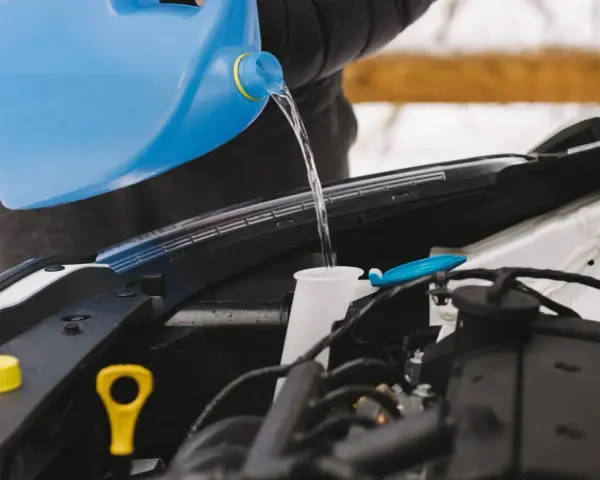 Personne verse du liquide dans le réservoir pour fabriquer lave glace. Le liquide coule d'une grande bouteille bleue vers le compartiment moteur.