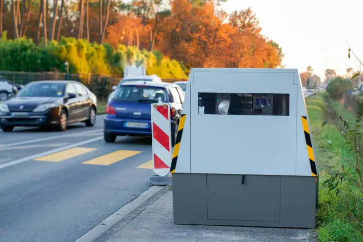 Un radar mobile de voiture surveille la route. Des voitures passent devant, dans un décor automnal.
