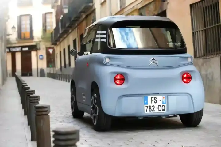 Citroën Ami bleu pastel dans une ruelle pavée. Peut-on acheter un véhicule sans contrôle technique ? Ce petit véhicule électrique est prêt à rouler.