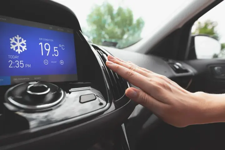 Main d'une personne vérifiant la sortie d'air climatisé dans une voiture, affichant 19.5°C. Parfait pour le clim air chaud.