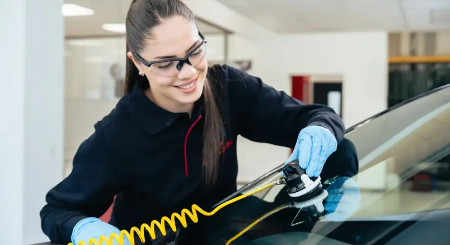 Une technicienne répare une fissure sur un pare-brise avec un équipement spécialisé. Elle sait exactement fissure pare brise que faire.