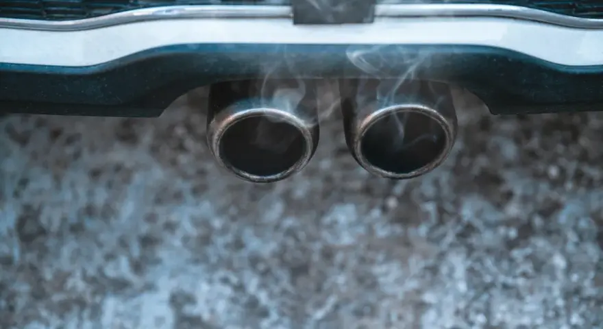 Vapeur d'eau sortant des deux pots d'échappement d'une voiture, suggérant un démarrage par temps froid.
