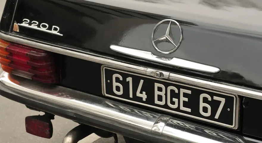 Arrière d'une Mercedes 220D noire. La plaque d'immatriculation "614 BGE 67" est visible. Pour savoir les chevaux de ma voiture, il faut regarder la carte grise.