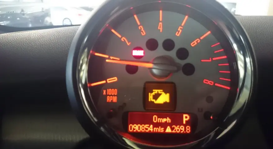 Tableau de bord d'une voiture avec voyant moteur allumé, indiquant un dysfonctionnement du système de contrôle des gaz d'échappement. Kilométrage : 90854 miles.