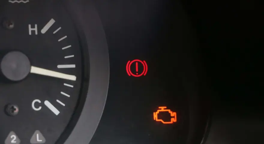 Tableau de bord d'une voiture avec le voyant moteur allumé, signalant un problème. Le voyant d'alerte de freinage est également visible.
