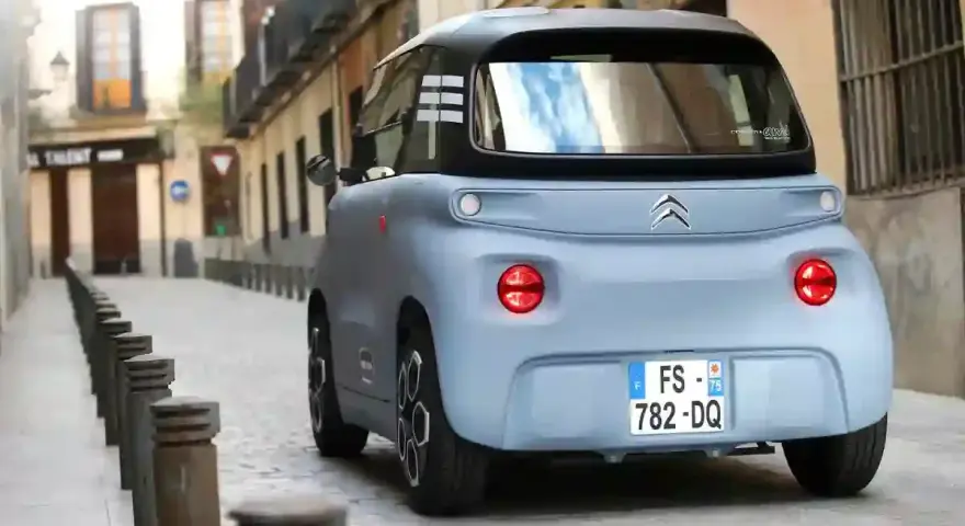 Citroën Ami bleu pastel dans une ruelle pavée. Peut-on acheter un véhicule sans contrôle technique ? Ce petit véhicule électrique est prêt à rouler.