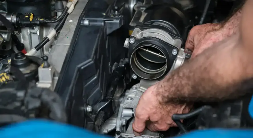 Mains d'un mécanicien travaillant sur un moteur, possiblement pour diagnostiquer un débitmètre d'air défectueux symptôme.