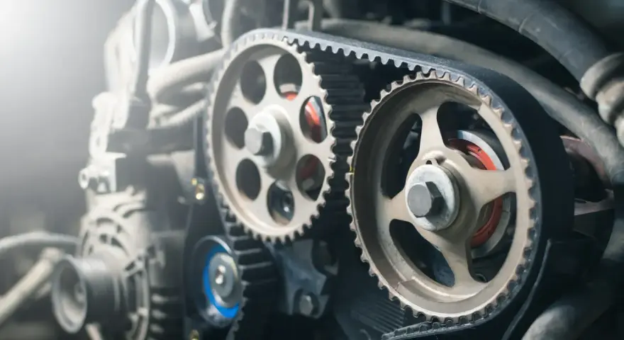 Courroie crantée et poulies d'un moteur, suggérant une distribution décalée ou un réglage précis.