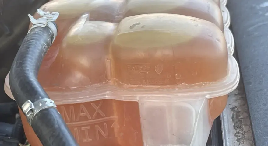 Le réservoir de liquide de refroidissement est plein, indiquant trop de liquide de refroidissement. Les marques MAX et MIN sont visibles.