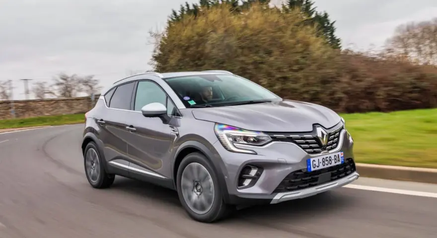 Une Renault Captur 2 grise roule sur une route sinueuse, prête pour son programme d'entretien.