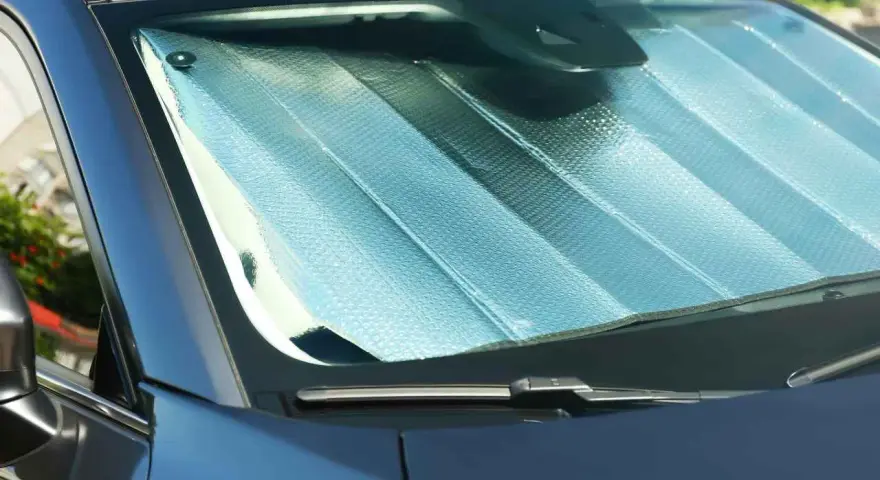 Pare-soleil argenté installé sur un pare-brise de voiture. Facile à mettre, il protège de la chaleur.