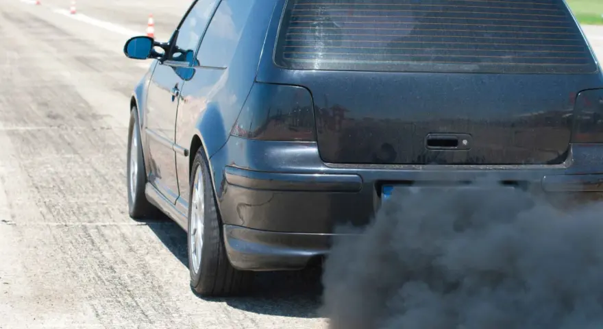 Voiture noire émettant une épaisse fumée noire sans perte de puissance, sur une piste.