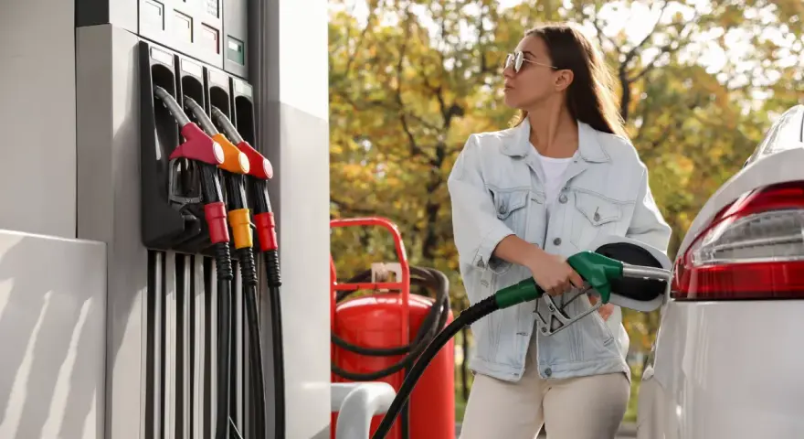 Femme faisant le plein d'essence, inquiète des symptômes de mauvais carburant voiture.