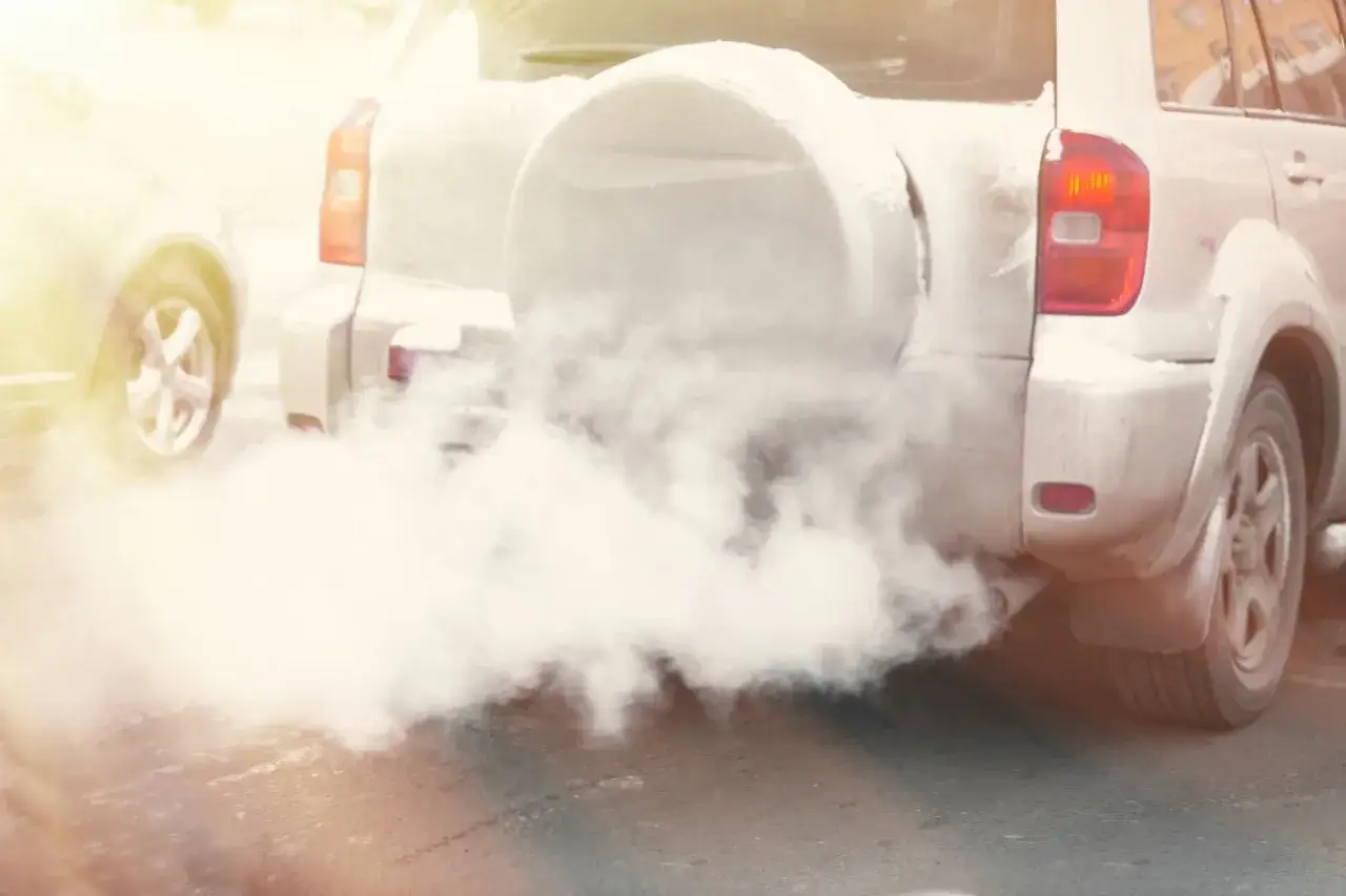 Fumée blanche épaisse sortant du pot d'échappement d'un SUV, suggérant de l'eau ou de la condensation.