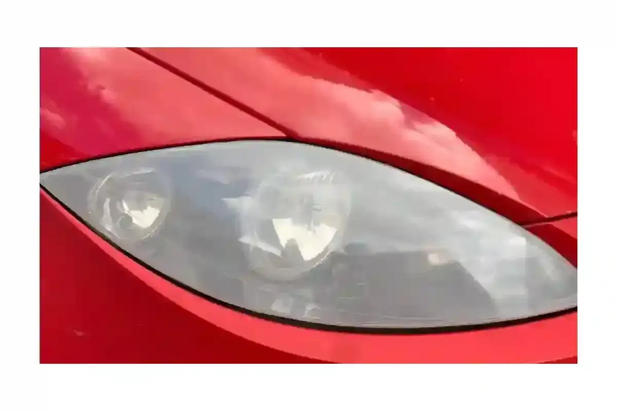 Phare de voiture rouge avec un phare opaque, prêt à être nettoyé pour retrouver sa clarté.