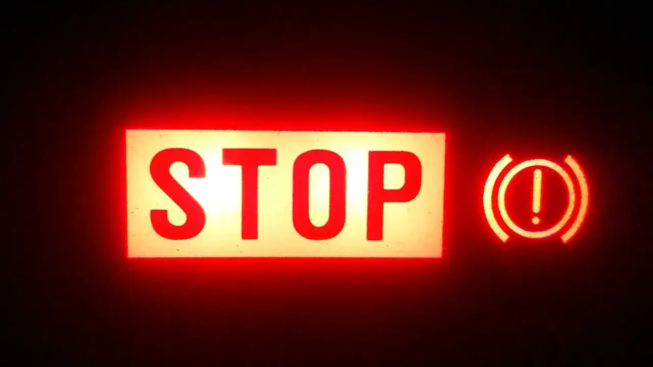 Voyant STOP allumé, avec le symbole d'un frein à main. Le niveau du liquide de frein est peut-être bas.
