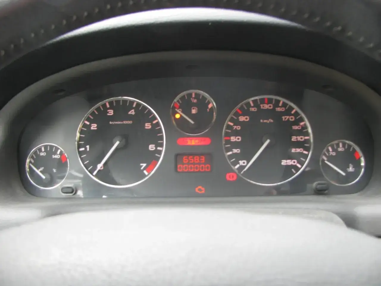 Tableau de bord d'une Peugeot 406 : compte-tours, compteur de vitesse, jauge de carburant et indicateur de température. Le voyant liquide de refroidissement est allumé.
