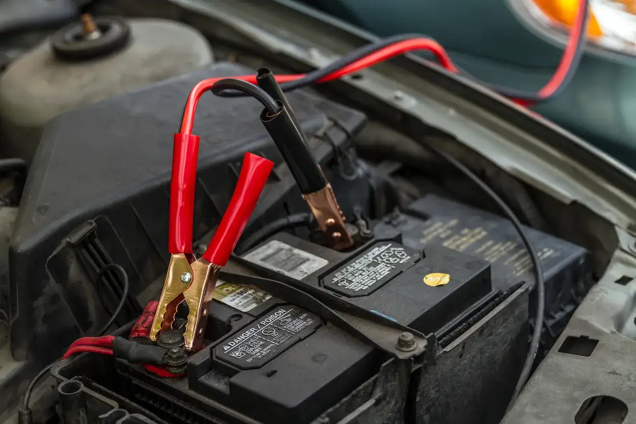 Pinces de démarrage connectées à une batterie de voiture, signe d'une panne batterie voiture.