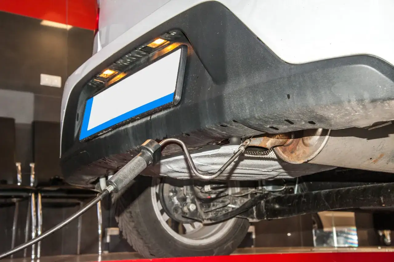 Sonde d'échappement insérée sous une voiture, suggérant un contrôle technique dépassé tolérance.