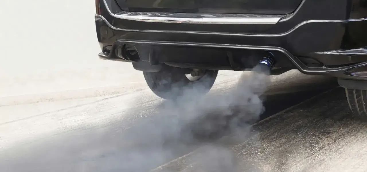 &Eacute;chappement d'un v&eacute;hicule &eacute;mettant une &eacute;paisse fum&eacute;e noire, signe d'une combustion incompl&egrave;te, mais le moteur semble toujours fonctionner sans perte de puissance.