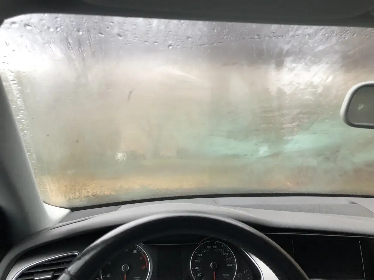 Pare-brise embu&eacute; dans la voiture, la visibilit&eacute; est r&eacute;duite. Des gouttes d'eau perlent sur la vitre.