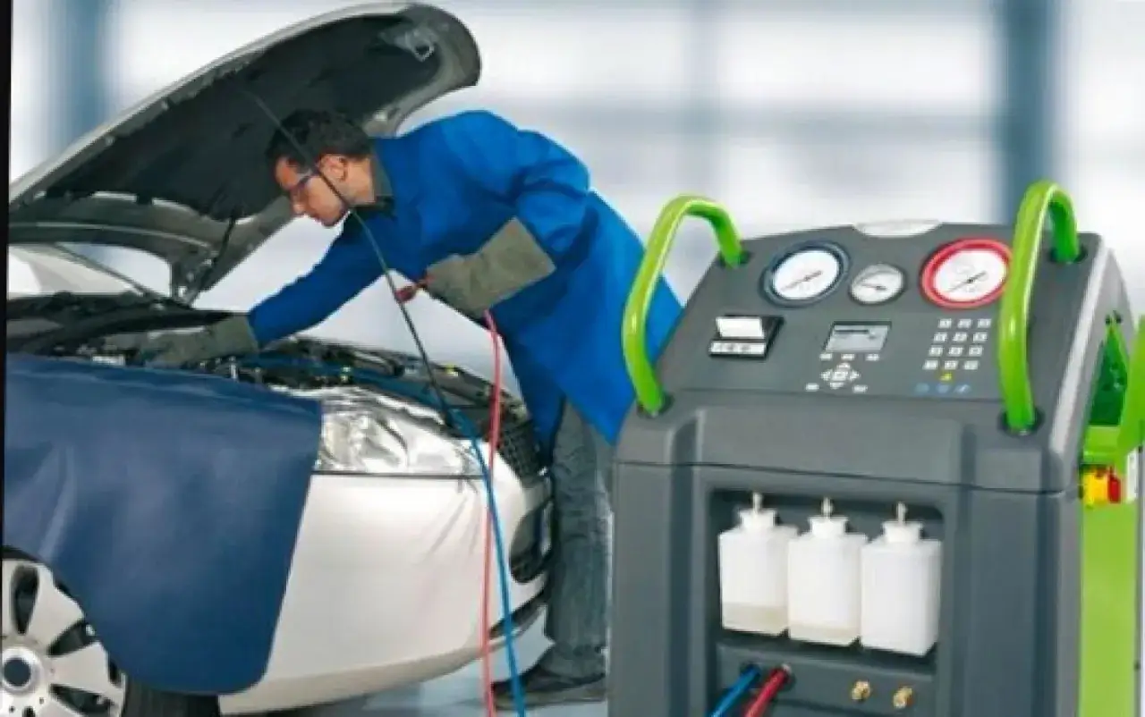 Un technicien utilise une machine pour vérifier la durée de recharge de la clim d'une voiture.